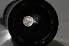 Canon nFD 70-150mm f4.5-5.6 lens seen from the front with a light shining through from behind to show dust and light scratches